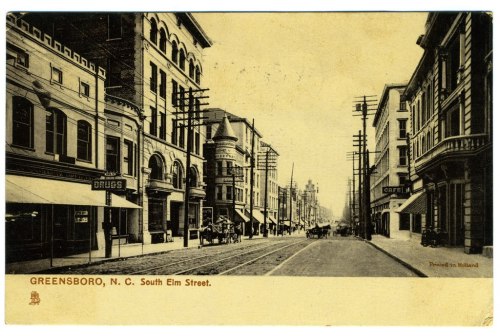 Historic postcard of South Elm Street in Greensboro, N.C., featuring buildings, streetcars, and horse-drawn carriages.