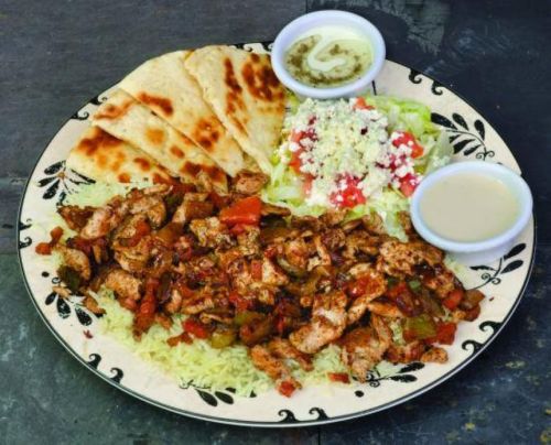 A colorful plate featuring grilled chicken, rice, flatbread, salad, and two dipping sauces.