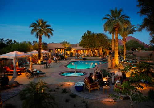 A serene evening scene of a pool area surrounded by palm trees, lounge chairs, and people enjoying the ambiance.