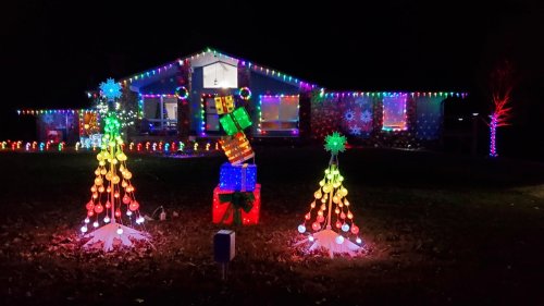 A brightly lit house decorated with colorful Christmas lights, featuring illuminated trees and festive decorations.