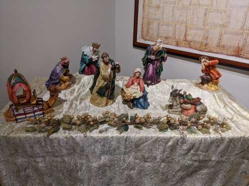 A nativity scene with figurines of Mary, Joseph, baby Jesus, and various biblical figures on a decorated table.