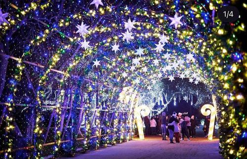 A vibrant, illuminated tunnel adorned with colorful lights and stars, with people walking through it.