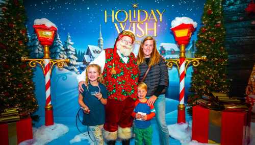 A family poses with Santa Claus in a festive setting, surrounded by holiday decorations and a snowy backdrop.