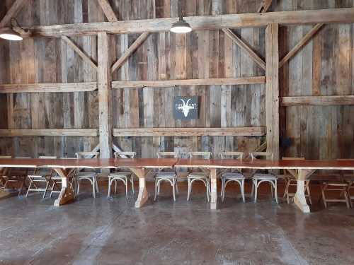 A rustic wooden interior featuring a long table and chairs against a weathered wood wall.