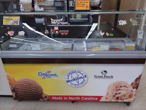 Ice cream display case featuring various flavors, with a sign for Mooresville Ice Cream Company, made in North Carolina.