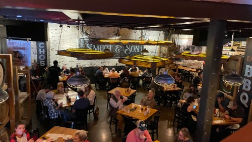 A bustling restaurant interior with wooden tables, diners enjoying meals, and warm lighting overhead.