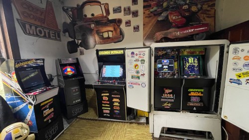 A cozy arcade room featuring vintage arcade machines and a Cars-themed mural on the wall.