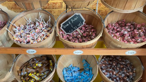 Baskets filled with colorful candies and lollipops, labeled for easy selection in a bright store setting.