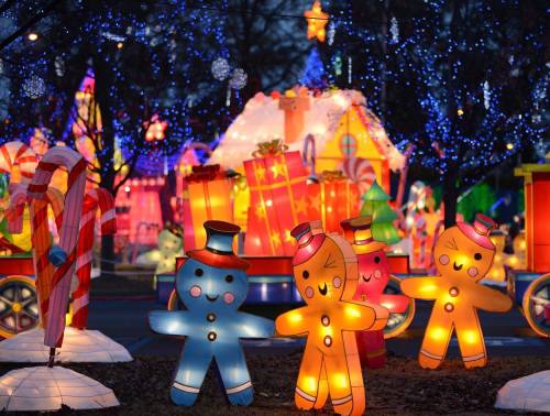 Colorful illuminated gingerbread figures in a festive holiday display with candy canes and gift boxes.