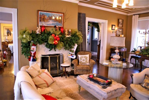 Cozy living room decorated for the holidays, featuring a fireplace, festive garland, and comfortable seating.