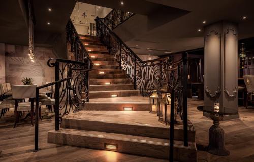 Elegant staircase with ornate black railing, warm lighting, and wooden steps, leading to a stylish interior space.