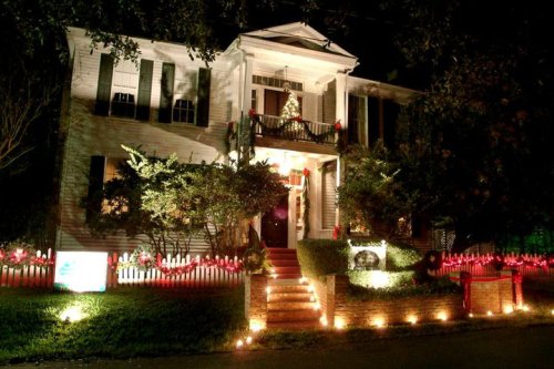 A beautifully decorated house at night, adorned with festive lights and a Christmas tree on the porch.