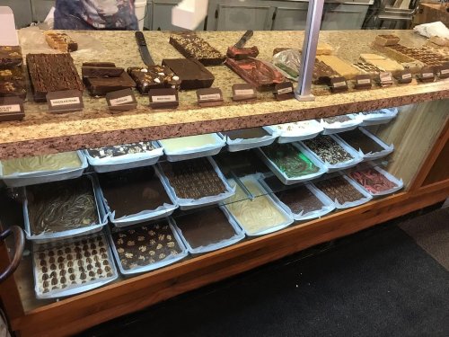 A display case filled with various types of fudge and chocolate treats, showcasing an array of flavors and textures.