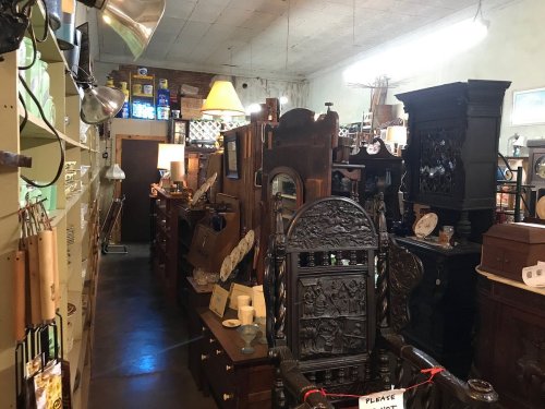 A vintage shop filled with various antique furniture and decor items, creating a cozy, cluttered atmosphere.