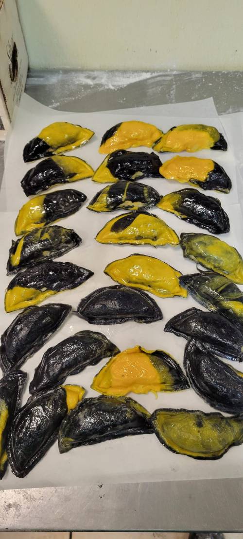 A tray of black and yellow pastry shells arranged neatly on parchment paper.