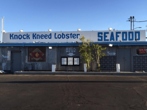 A seafood restaurant named "Knock Kneed Lobster" with a rustic exterior and signs indicating it's open.