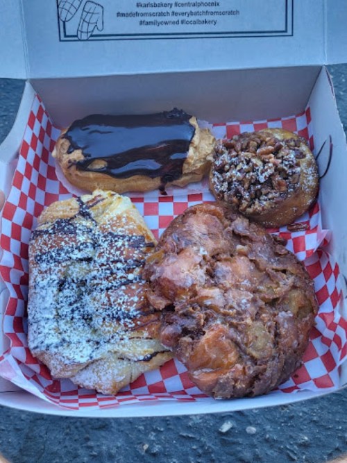 A box of assorted pastries, including a chocolate-covered eclair, a cinnamon roll, and a fruit-filled danish.