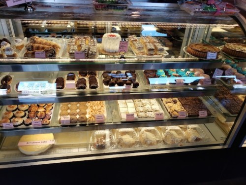 A display case filled with various baked goods, including cakes, cookies, and pastries, all beautifully arranged.