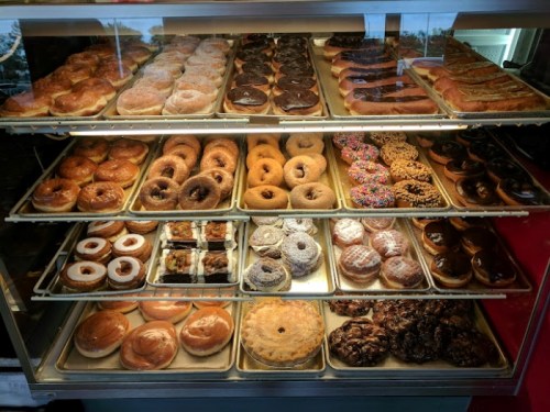 A display case filled with a variety of donuts, including glazed, chocolate, and sprinkled options.