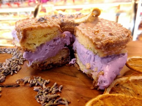 A cross-section of a lavender-flavored cake with creamy purple filling, surrounded by dried lavender and orange slices.