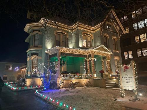 A beautifully lit historic house at night, adorned with holiday decorations and colorful lights.