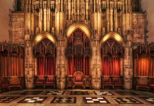 Gothic-style interior featuring ornate arches, red drapes, and wooden chairs in a historic setting.