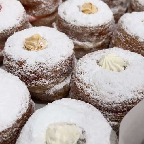 A close-up of powdered sugar-dusted donuts filled with cream, arranged in a tempting display.