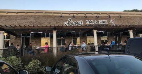 Exterior view of Laura's Bar & Grill with diners seated outside on a patio during sunset.