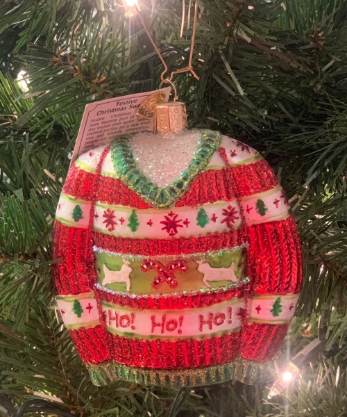 A festive Christmas sweater ornament in red and green, decorated with snowflakes, trees, and "Ho! Ho! Ho!" text.