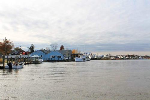 A calm waterfront scene with boats docked, colorful buildings, and a cloudy sky reflecting on the water.