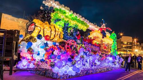 A colorful parade float adorned with balloons and lights, featuring festive decorations and a whimsical design.