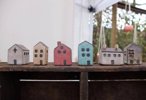 A row of small, colorful ceramic houses displayed on a wooden surface, each with unique designs and details.