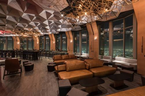 Stylish lounge with geometric ceiling, leather sofas, and city views at night. Modern decor and ambient lighting.