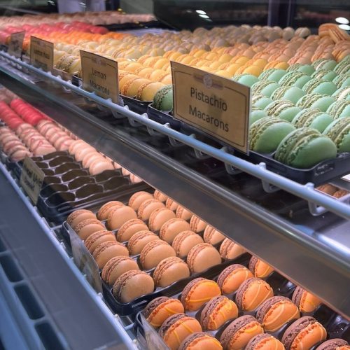 A display case filled with colorful macarons in various flavors, including lemon and pistachio.