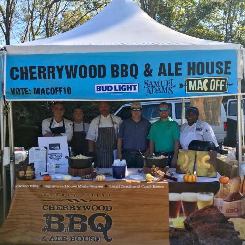 A BBQ and ale house booth with staff posing under a tent, featuring branding for Bud Light and Samuel Adams.