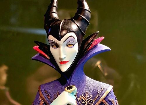 A close-up of a stylized figurine of a character with horns, wearing a purple outfit and holding a small object.