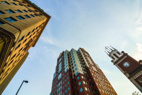 A low-angle view of two buildings, one historic and ornate, the other modern, against a clear blue sky.