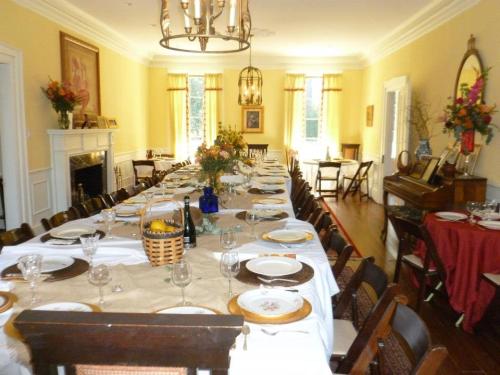 A spacious dining room set for a large meal, featuring a long table with plates, glasses, and floral centerpieces.