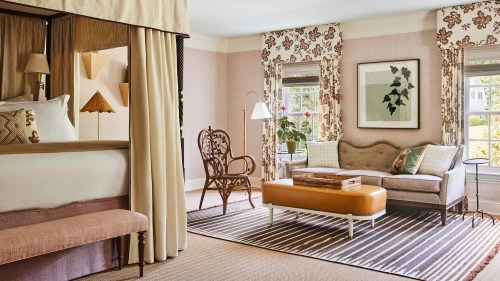 Cozy hotel room featuring a bed, elegant seating area, and floral decor with natural light streaming in.