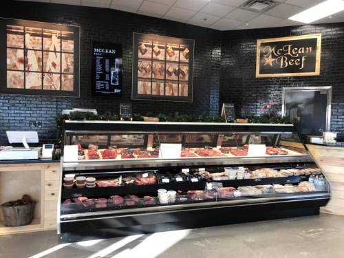 A meat display case filled with various cuts of beef and packaged products in a rustic market setting.