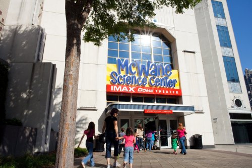 Entrance of the McWane Science Center with visitors walking in, featuring an IMAX Dome Theater sign.