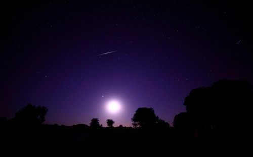 A night sky filled with stars, featuring a bright moon and a shooting star against a purple backdrop.