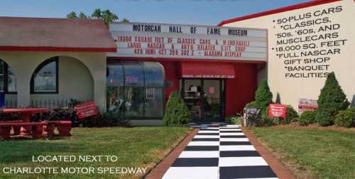 Exterior view of the Motorcar Hall of Fame Museum, featuring classic cars and a checkered pathway leading to the entrance.