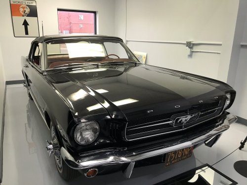A classic black Ford Mustang parked indoors, showcasing its sleek design and shiny exterior.