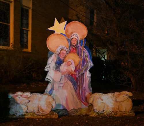 Nativity scene featuring Mary, Joseph, and baby Jesus with sheep and a star in a nighttime setting.