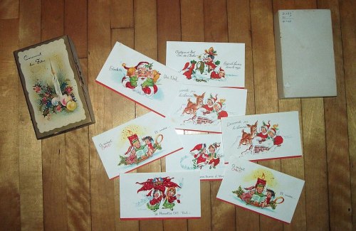 A collection of vintage holiday cards and a decorative box on a wooden surface.