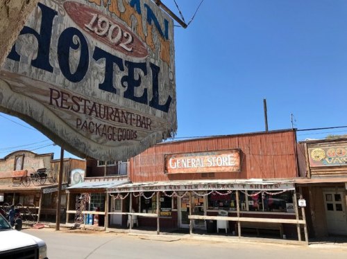 A rustic hotel and general store in a historic western town, featuring vintage signage and a clear blue sky.