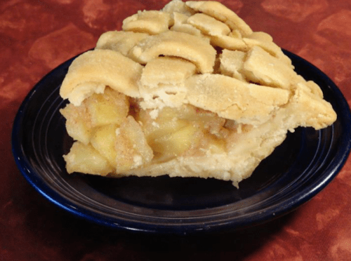 A slice of apple pie with a golden, lattice crust on a blue plate, showcasing the apple filling inside.