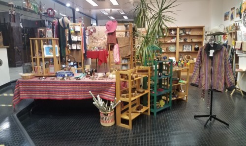 A vibrant display of handmade crafts, clothing, and decor in a cozy shop setting with wooden shelves and colorful items.
