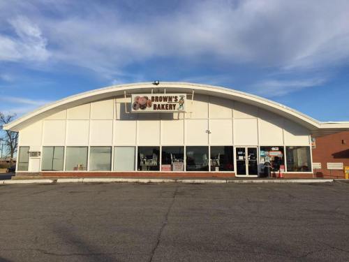 A large bakery building with a curved roof, featuring a sign that reads "Brown's Bakery" and large windows.